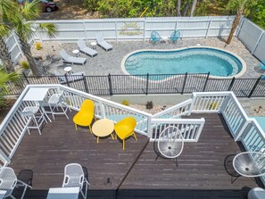 En terrasse med udendørs siddepladser, en swimmingpool og et indhegnet område.