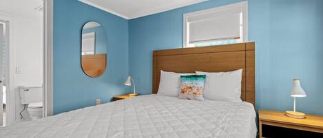 A bedroom with a large bed, a wooden headboard, a round mirror, and two bedside tables with lamps.