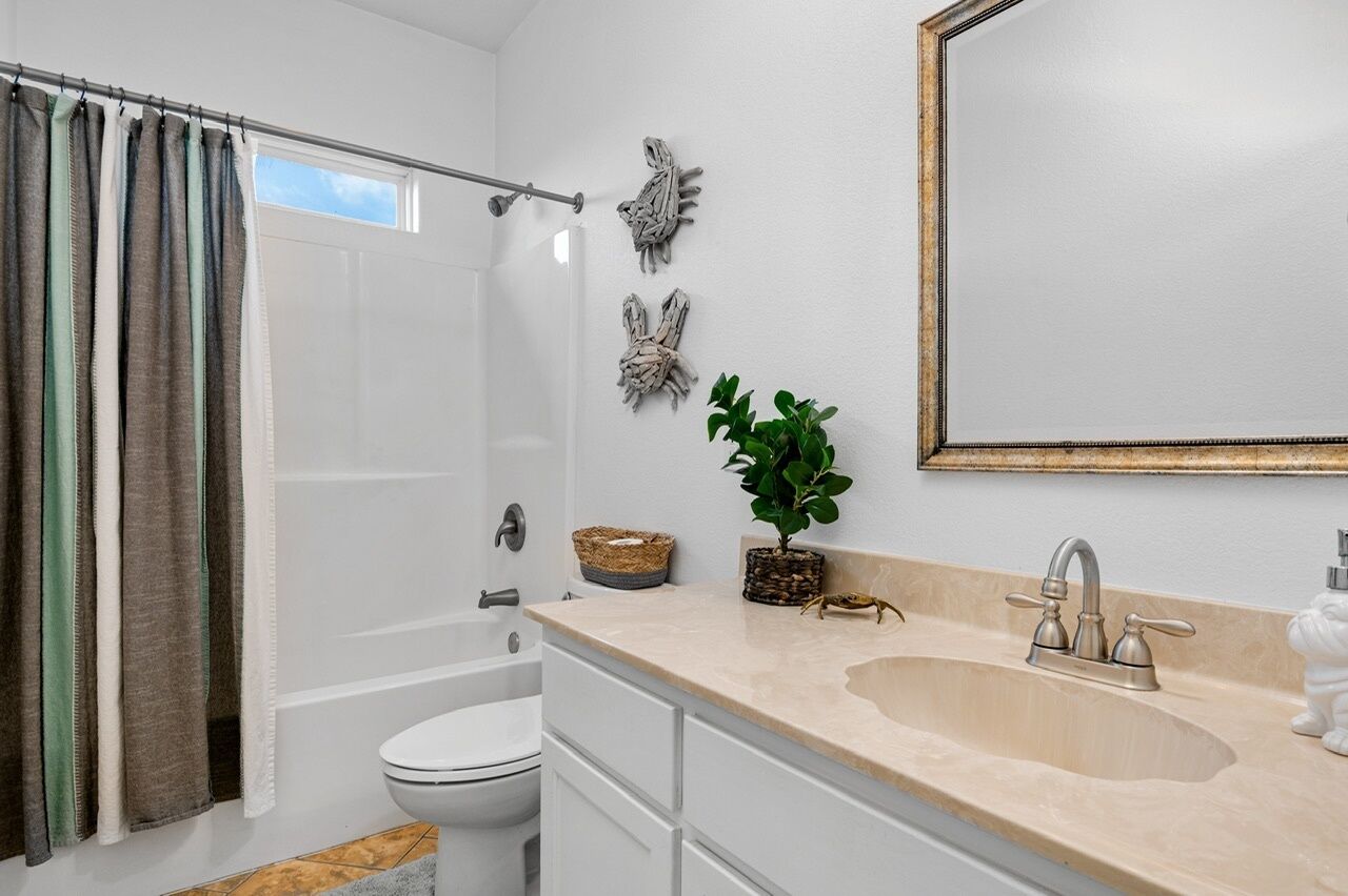 Une salle de bain moderne avec une baignoire, des toilettes et un lavabo. On y trouve des éléments décoratifs sur les murs et une plante en pot sur le meuble-lavabo.
