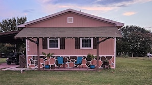 A two-story building with a covered patio area. - Kingdom Home Country Cottage is where you can relax, rejuvenate and enjoy peace. (Waxahachie)