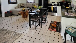 A living room with a dining table, sofa, and a kitchen area with cabinets and appliances. - Kingdom Home Country Cottage is where you can relax, rejuvenate and enjoy peace. (Waxahachie)