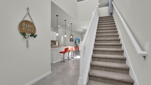A staircase leading to a kitchen area with a bar and seating. - The Force At Solterra By Shine Villas #041 6 Bedroom Villa (Davenport)