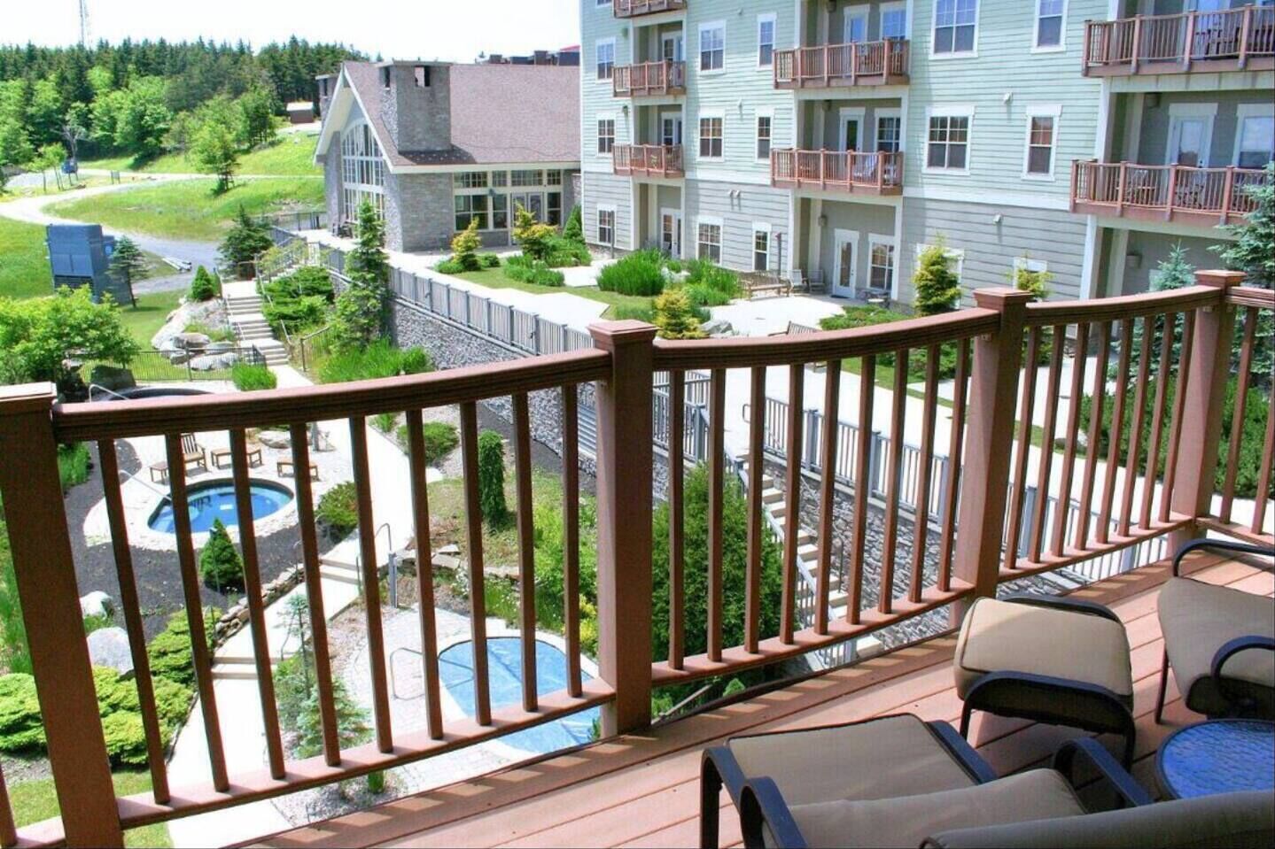 A balcony with a pool, outdoor furniture, and a view of a multi-story building with balconies.