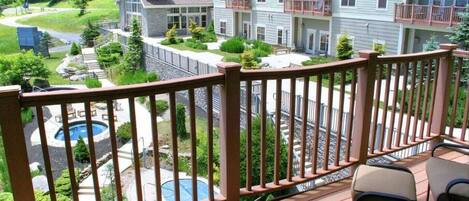 A balcony with a pool, outdoor furniture, and a view of a multi-story building with balconies.