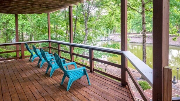 Een houten terras met blauwe stoelen met uitzicht op water en bomen.