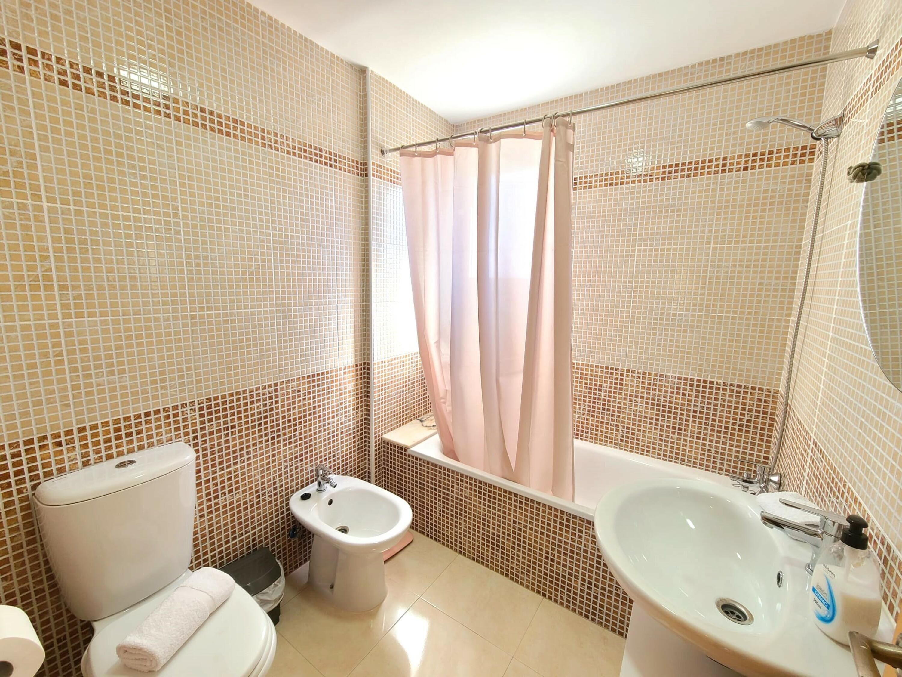 A bathroom with a toilet, bidet, bathtub, and sink.