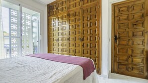 Ein Schlafzimmer mit einem großen Bett, einem Holzschrank und einer Schiebetür aus Glas.