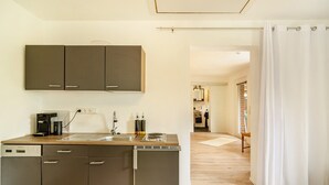 Una cocina compacta con lavavajillas, cafetera y una hornilla pequeña.