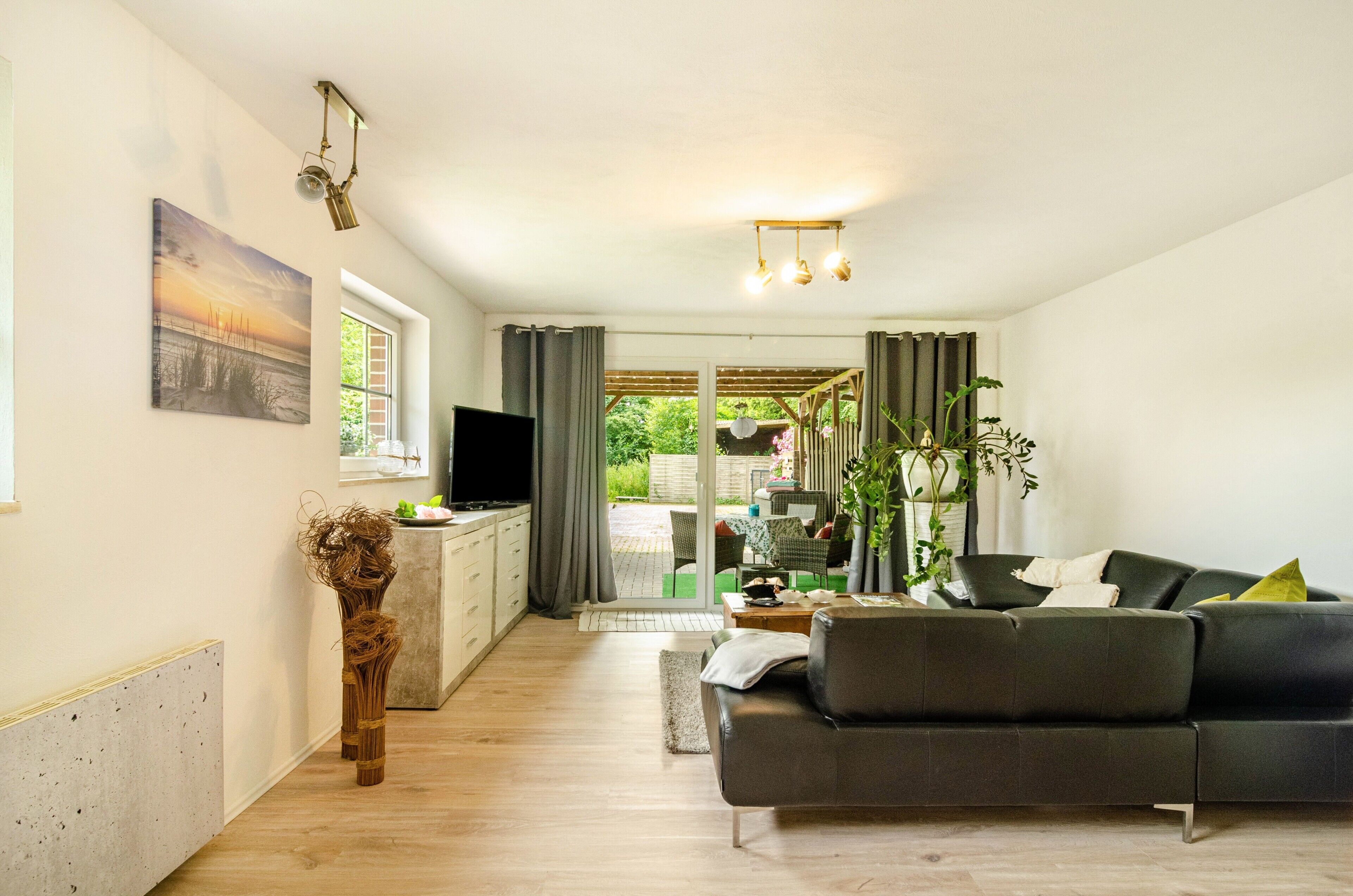 Una sala de estar moderna con un sofá, televisor y un comedor con mesa y sillas.