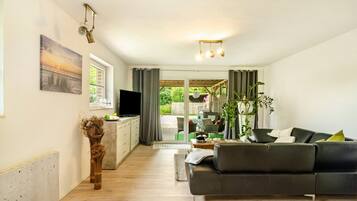 Una sala de estar moderna con un sofá, televisor y un comedor con mesa y sillas.