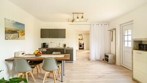 Una cocina moderna con comedor, vista al salón y una pequeña mesita auxiliar.