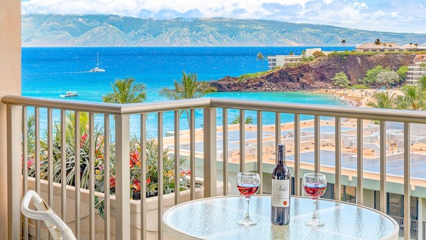 A balcony with a table, two wine glasses, and a bottle of wine.