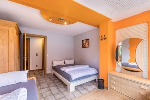 Ein Schlafzimmer mit einem Bett, einem Schminktisch, einem Spiegel und einer Tür zu einem anderen Raum.