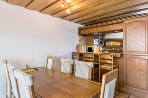 Ein Essbereich mit Holztisch und -stühlen, eine Küche mit Holzschränken sowie eine Mikrowelle.