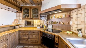 A kitchen with wooden cabinets, a built-in oven, a microwave, and a stainless steel sink.