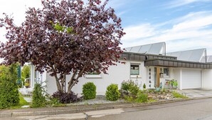 A modern house with a solar panel roof, a driveway, and a well-maintained garden. - Holiday Apartment 'Leicht' with Wi-Fi (Münsingen)