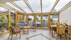 A conservatory with wicker furniture, glass doors, and a tiled floor. - Holiday Apartment 'Leicht' with Wi-Fi (Münsingen)