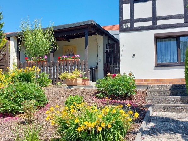 A house with a garden, a wooden fence, and a number '12' on the building.