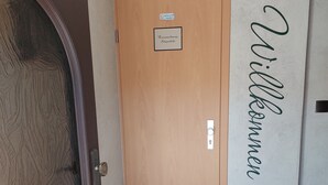 Una puerta de madera con un letrero que indica una habitación privada, una pared con un nombre y un felpudo.