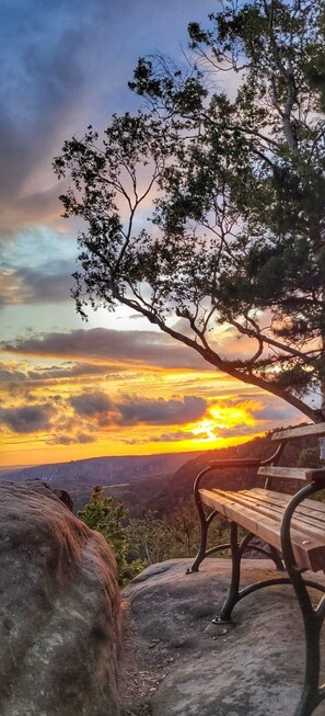 A bench overlooking a sunset with a mountainous landscape.