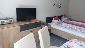 Ein Schlafzimmer mit einem Bett, einem Fernseher, einer Holzkommode und einem Schreibtisch.