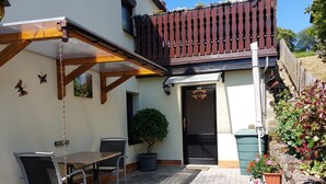 Eine Terrasse mit Tisch und Stühlen, einer Hängeschaukel, einem Blumentopf und einem Holzzaun.