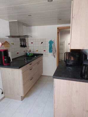 A compact kitchen with a black countertop, wooden cabinets, a white tiled backsplash, and a visible stove. - Apartment "Rittergut" with Private Terrace & Wi-Fi (Struppen)
