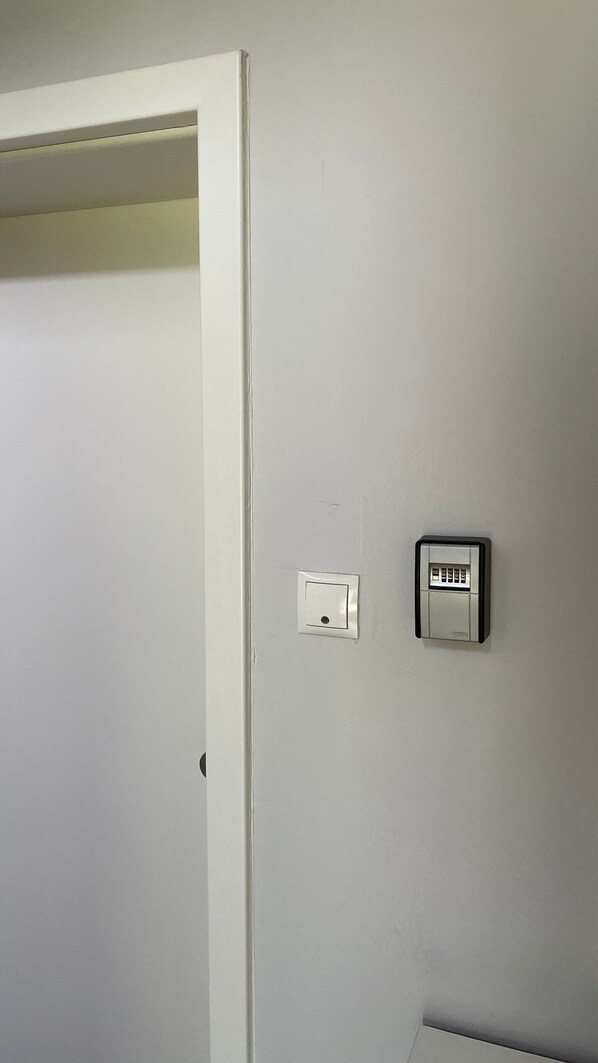 Une porte blanche avec un interrupteur et un clavier de sécurité fixés au mur.