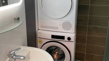 Un bagno compatto e moderno dotato di lavatrice e asciugatrice integrate, lavabo e specchio.