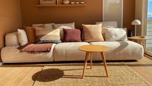 Una sala de estar acogedora con un sofá color beige, una mesa de centro redonda de madera y un tapiz tejido.