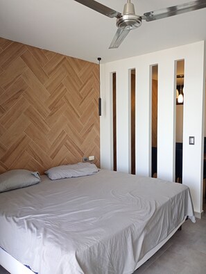 Relax in this serene bedroom featuring a large bed and a herringbone-patterned floor.