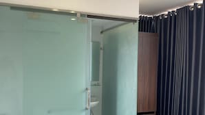 Een badkamer met een douchecabine met glazen wanden, een houten kastje en een toilet.