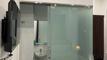 Un bagno con cabina doccia in vetro, un lavandino e uno specchio.