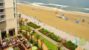 A beach view with a hotel building, a pool area, and a sandy beach. - Luxury Beachfront Resort Studio w/Kitchenette in VA Beach Sleeps 2 (Virginia Beach)
