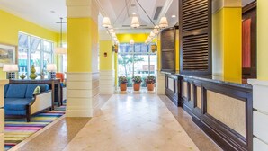 A hotel lobby with a bright yellow wall, a blue sofa, and a tiled floor. - Luxury Beachfront Resort Studio w/Kitchenette in VA Beach Sleeps 2 (Virginia Beach)