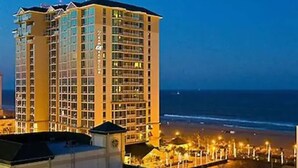 A multi-story hotel with balconies, located near a beach with a well-lit promenade. - Luxury Beachfront Resort Studio w/Kitchenette in VA Beach Sleeps 2 (Virginia Beach)
