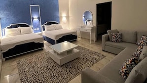 A modern hotel room with two beds, a sofa, a coffee table, and a small desk with a mirror. - Lucky Hostel (Cairo)