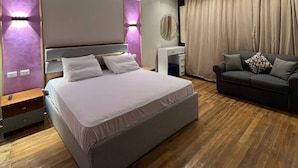 A modern hotel room with a large bed, bedside tables, a sofa, and a ceiling fan. - Lucky Hostel (Cairo)