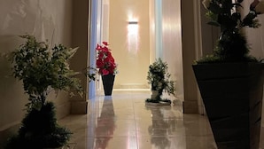 A hallway with a tiled floor, leading to a door at the end. There are potted plants on either side of the hallway. - Lucky Hostel (Cairo)