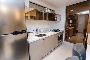 A modern kitchen with stainless steel appliances, a built-in oven, and a sink. - Fortune Cabo Branco (João Pessoa)