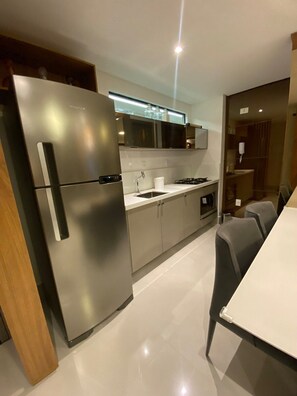 Una cocina moderna con electrodomésticos de acero inoxidable, una encimera blanca y un comedor con mesa y sillas.