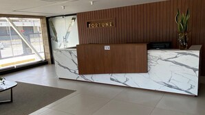 Un mostrador de recepción moderno con encimera de mármol y paneles de madera, con la etiqueta "FORTUNE".