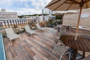 A rooftop terrace with outdoor seating, a pool, and city views.