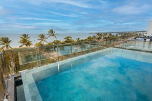 Piscina infinita no terraço, com vista clara para a praia e o oceano.