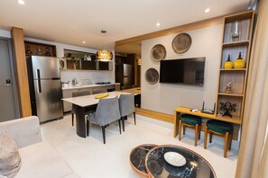 Una cocina moderna con comedor, televisor montado en la pared y un pequeño rincón de estar con mesa y sillas.