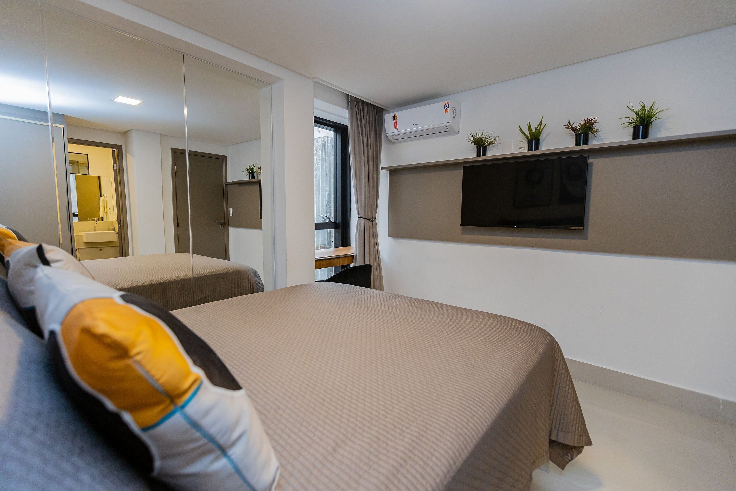A modern hotel room with two beds, a TV, and a window with curtains.
