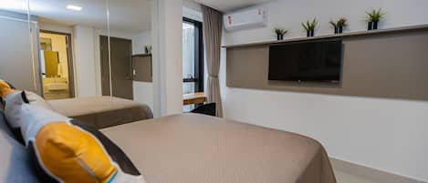 A modern hotel room with two beds, a TV, and a window with curtains.