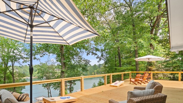 A wooden deck with wicker furniture, a wooden table, and striped umbrellas. - Carols Cottage - Double decker dock! Popular location! (Cullman)