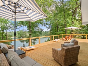 Une terrasse en bois avec des meubles en osier, une table en bois et des parasols à rayures.