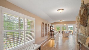A spacious hallway with a bench, large windows with blinds, a staircase, and a stone wall. - Carols Cottage - Double decker dock! Popular location! (Cullman)